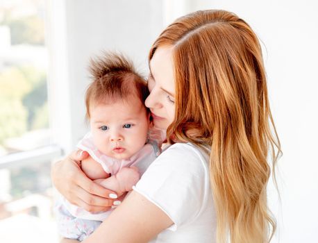 Happy mother kissing cute baby holding her up