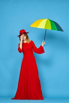 woman in red dress multicolored umbrella blue background. High quality photo