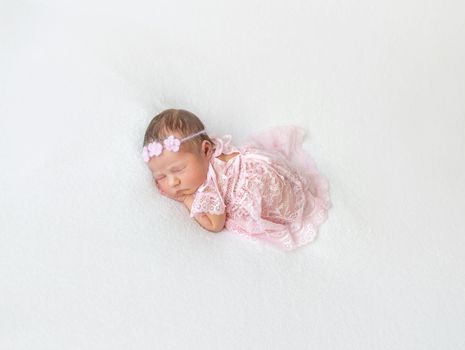 Cute princess baby napping in a laced pink suit wearing lovely hairband