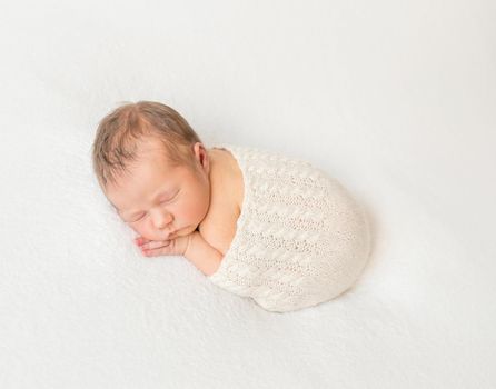 Adorable child napping covered with scarf, hairy little infant, hands under cheek