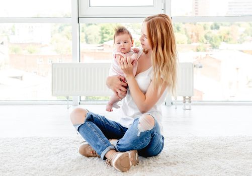 Happy mother kissing cute baby holding her up