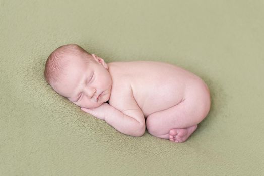lovely newborn baby sleeps curled up, top view