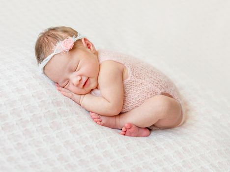lovely newborn girl sleeping on pink blanket with bare feet