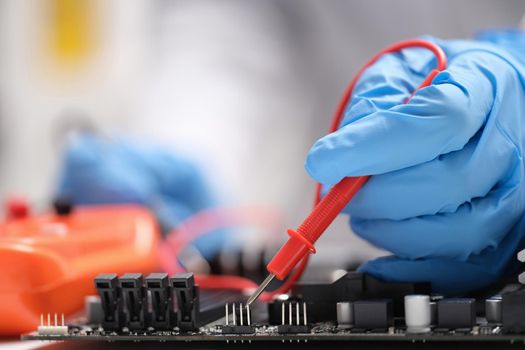 Master repairer testing motherboard with feeler gauge closeup. Repair and maintenance of computer equipment and electronics concept