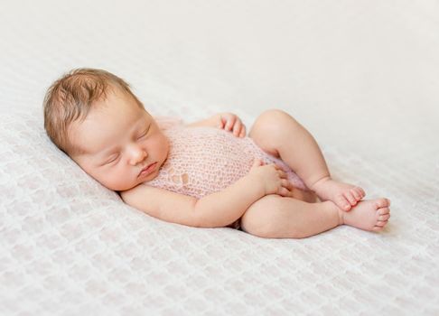 lovely newborn girl sleeping on pink blanket with bare feet