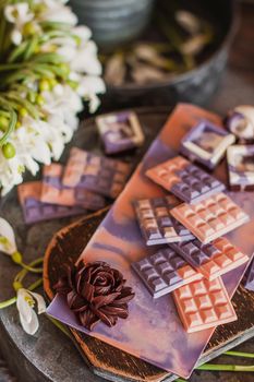 Assortment of luxury colored bonbons. Exclusive handmade chocolate candy. Springtime, Womans Day, Valentines Day concept. Pink and violet with dark chocolate flower.