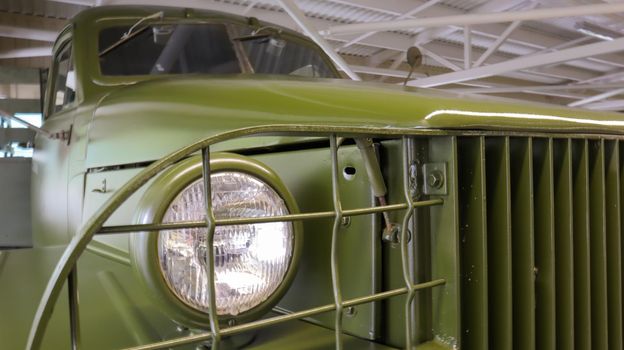Close-up is the round headlight of a khaki military truck. The three-axle truck was produced from 1941 to 1945. Increased cross-country ability and carrying capacity. Ukraine, Kiev - June 09, 2021