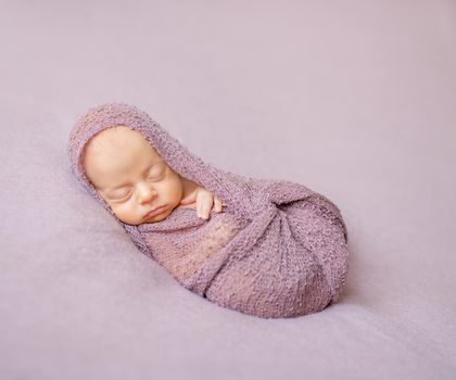 lovely sleeping newborn baby swaddled in pink diaper