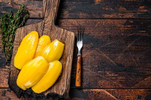 Preserve mango slices on a wooden board. Dark wooden background. Top view. Copy space.