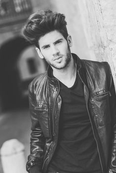 Portrait of a young handsome man, model of fashion, with modern hairstyle in urban background wearing and leather jacket