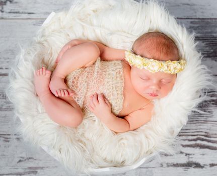 sweet sleeping newborn girl on round bed with fluffy blanket in funy pose