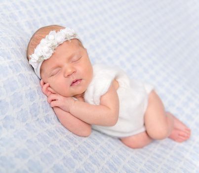 sweet newborn girl sleeping on her hands with flowers on headband