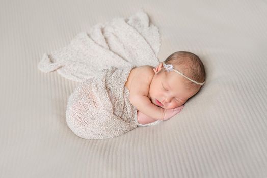 lovely smiling sleeping infant wrapped in gray warm diaper