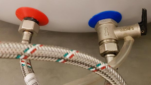 Connection of water supply, hot and cold water to the boiler. Hose for hot and cold water in the bathroom. Plumbing connections for a domestic electric water heater