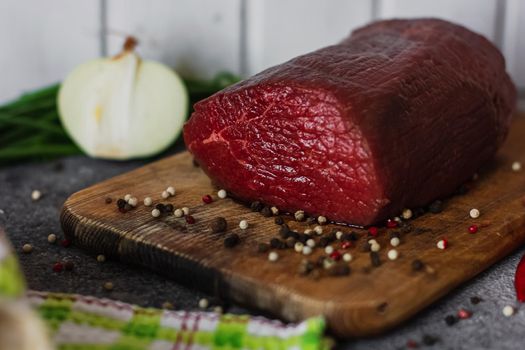 Raw meat. A large piece of beef chop on a wooden cutting board with pepper and spices.