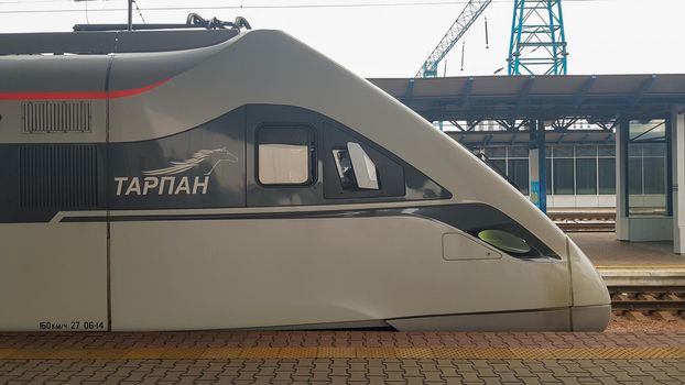 The high-speed passenger electric train Hyundai Rotem Tarpan HRCS2 Intercity stands on the platform of the central railway station in Kiev. Ukrainian railways. Ukraine, Kiev - June 09, 2021