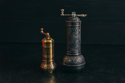 Pepper or coffee vintage metal grinder on a dark black background.