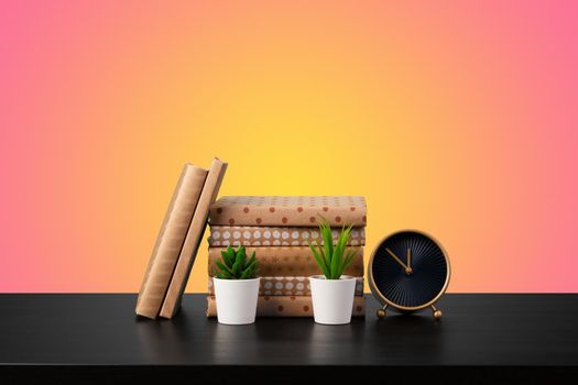 Education concept with stack of books on a table against colored background, front view