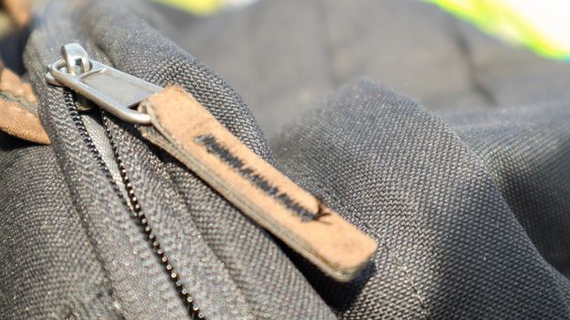 Zipper black bag backpack textile accessories. Close-up view of the clasp. Textile, metal and brown leather