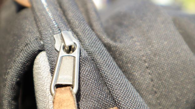 Zipper black bag backpack textile accessories. Close-up view of the clasp. Textile, metal and brown leather