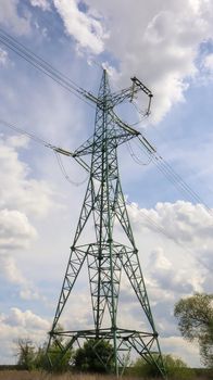 One tower, high voltage power lines. High voltage cables. High voltage electrical tower on the field. against the blue sky. Vertical photography