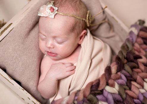 Cute little baby in knitted brown suit sweetly sleeping on the woolen blanket in little bed