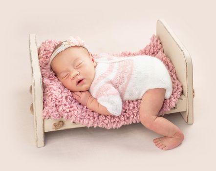 Little cutie infant in neatly knitted bodysuit on baby bed, isolated on white background