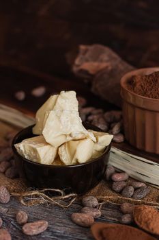 Unsweetened baking block chocolate, cocoa powder, cocoa butter and cocoa beans on old wooden background.