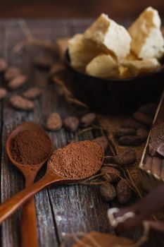 Unsweetened baking block chocolate, cocoa powder, cocoa butter and cocoa beans on old wooden background.