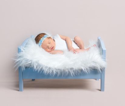 Lovely girl napping on wooden blue bed, lying on her side, hand under the cheek