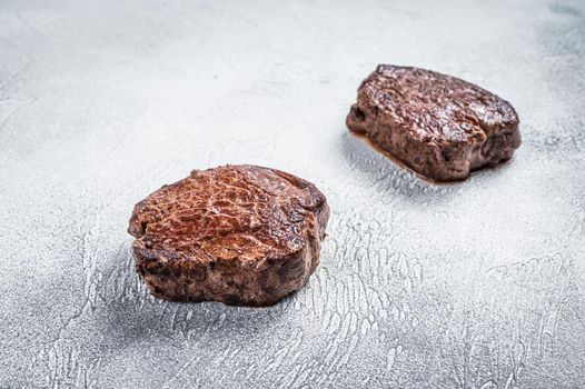 Grilled fillet mignon or tenderloin beef steak on kitchen table. White background. Top view.