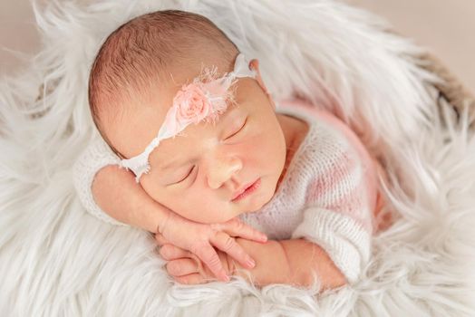 Cute baby with white rosary headband in soft shaggy blanket