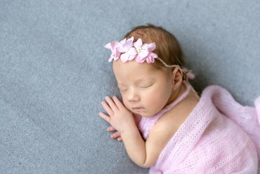 Adorable little girl napping on her side, dressed in a sweet pink dress, closeup