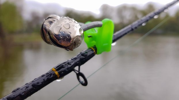 Silver fishing bells are worn on a fishing rod while fishing. Bite-call signal, at the tip of the rod. A bite alarm will alert you to a bite. Fishing tackle close-up