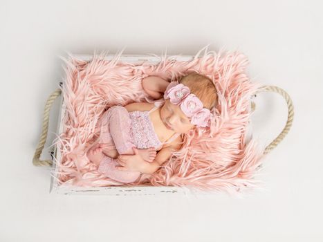 Lovely small girl sleeping in funny pose dressed in pinked laced suit, topshot