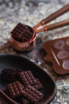 Assortment of different chocolate types in wooden carved plate, with vintage props on the background.