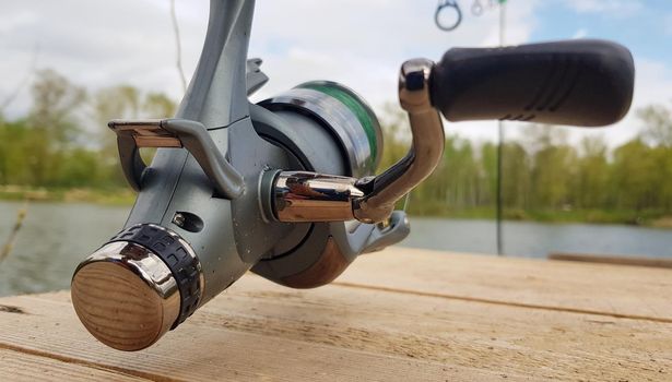Carp fishing rod isolated on the lake and wooden bridge. Carp feeder spinning reel close up. Fishing for carp on the lake. Fisherman's equipment