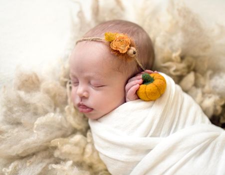 Little cute baby covered with white coverlet sweetly sleeping on woolen blanket