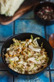 Salad with cabbage, eggs, corns and meat on the plate on rustic tiled table.