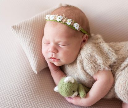 Cute new born child sleeping on pillow with green little toy