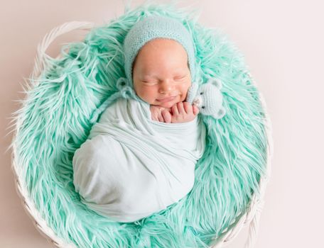 Lovely newborn resting in child sleeping basket with wool