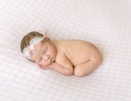 Little nude baby girl speeping on her belly wearing flowery headband, sweet dreams