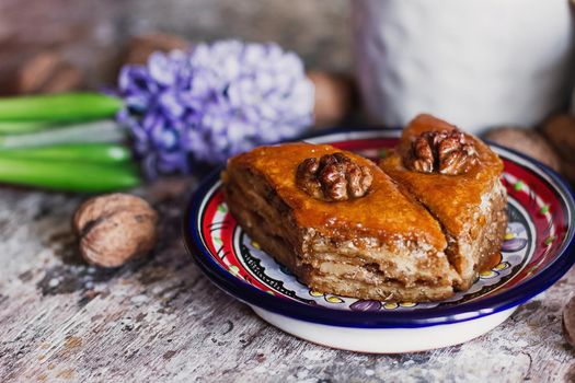 Assorted baklava. A Turkish ramadan arabic sweet dessert on a decorative plate, with coffee cup in the background. Middle eastern food baklava with nuts and honey syrup.