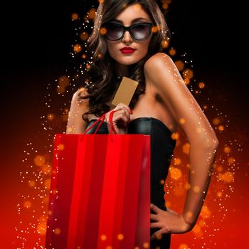 Beautiful young woman make shopping in black friday holiday. Girl with black bag on dark background.