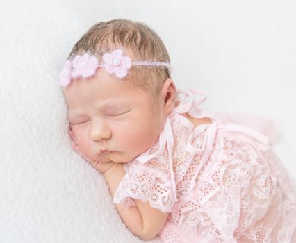 Cute princess baby napping in a laced pink suit wearing lovely hairband