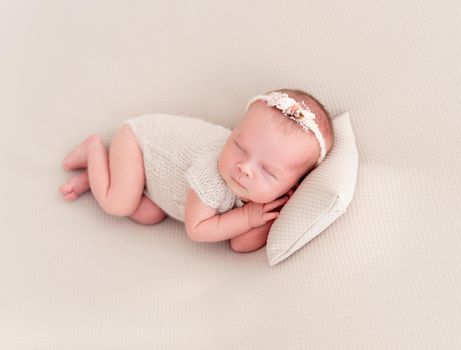 newborn baby girl sleeping sweetly on a little pillow