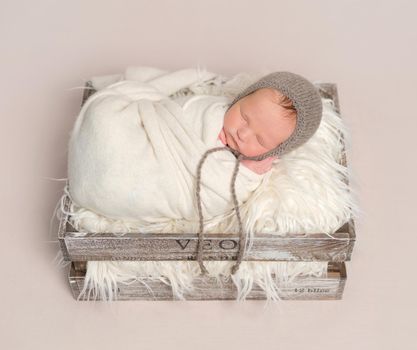 Cute baby napping in a basket for kids, wrapped up creatively in white blanket, topview