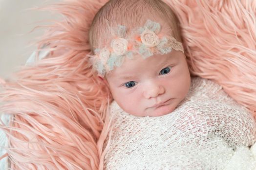 Cute baby girl watching the world, big curious eyes, wearing a lovely flowery hairband, topview