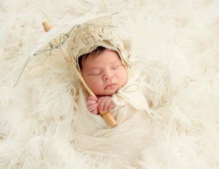 newborn baby girl sleeping sweetly with decorative umbrella