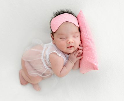 newborn baby girl sleeping sweetly on a little pillow